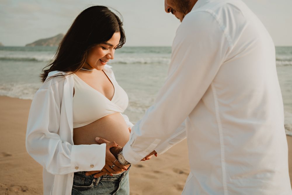 Husband lovingly embracing his wife’s baby bump, a tender moment in this Mazatlán shoot