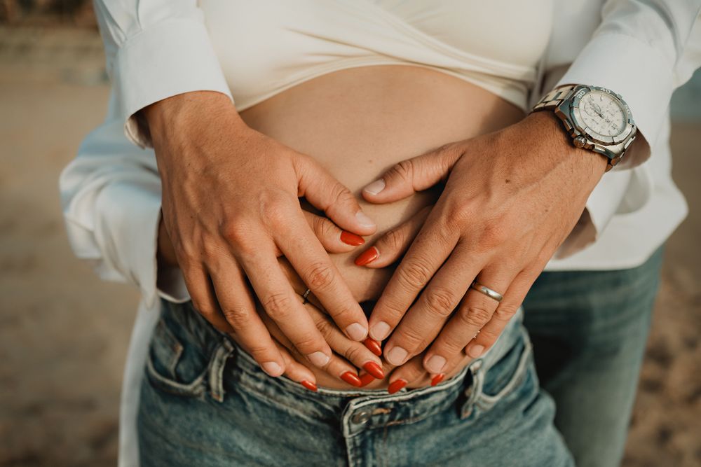 Hands forming a heart over the baby bump, a sweet touch in their Mazatlán pregnancy session