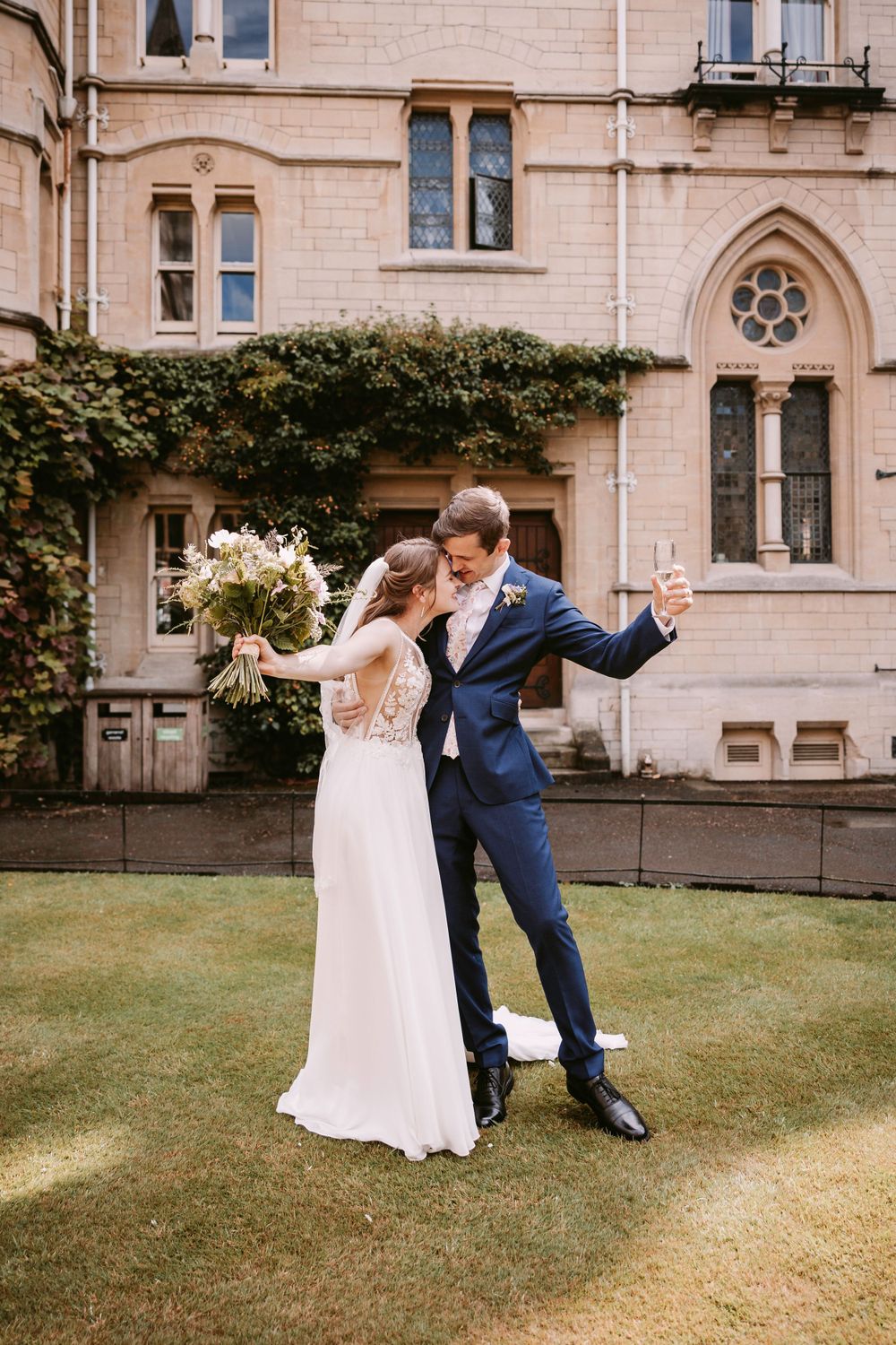 Couple shares romantic dance pose on lawn in front of stone building at Balliol College, Oxford