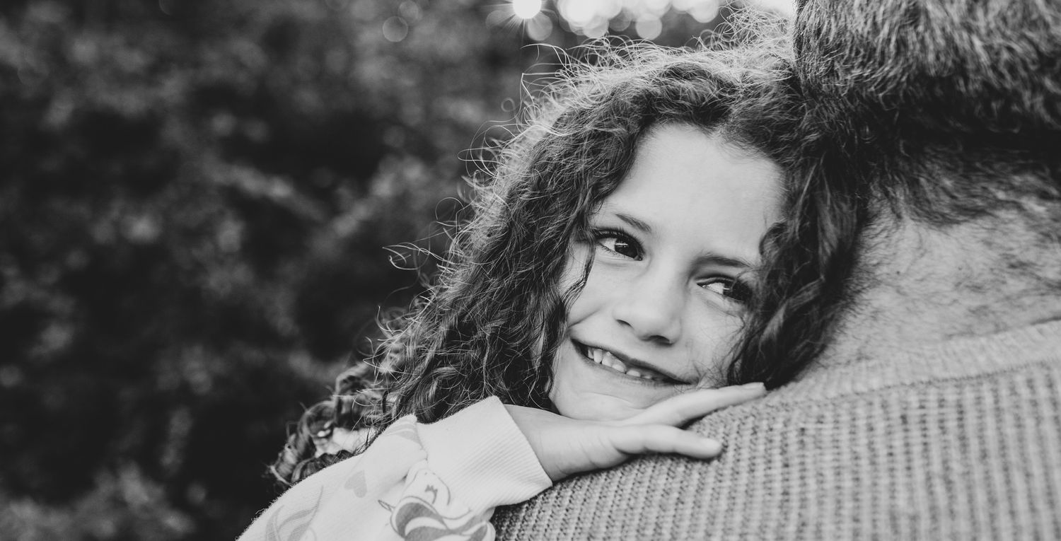 Close-up portrait of smiling child with curly hair.