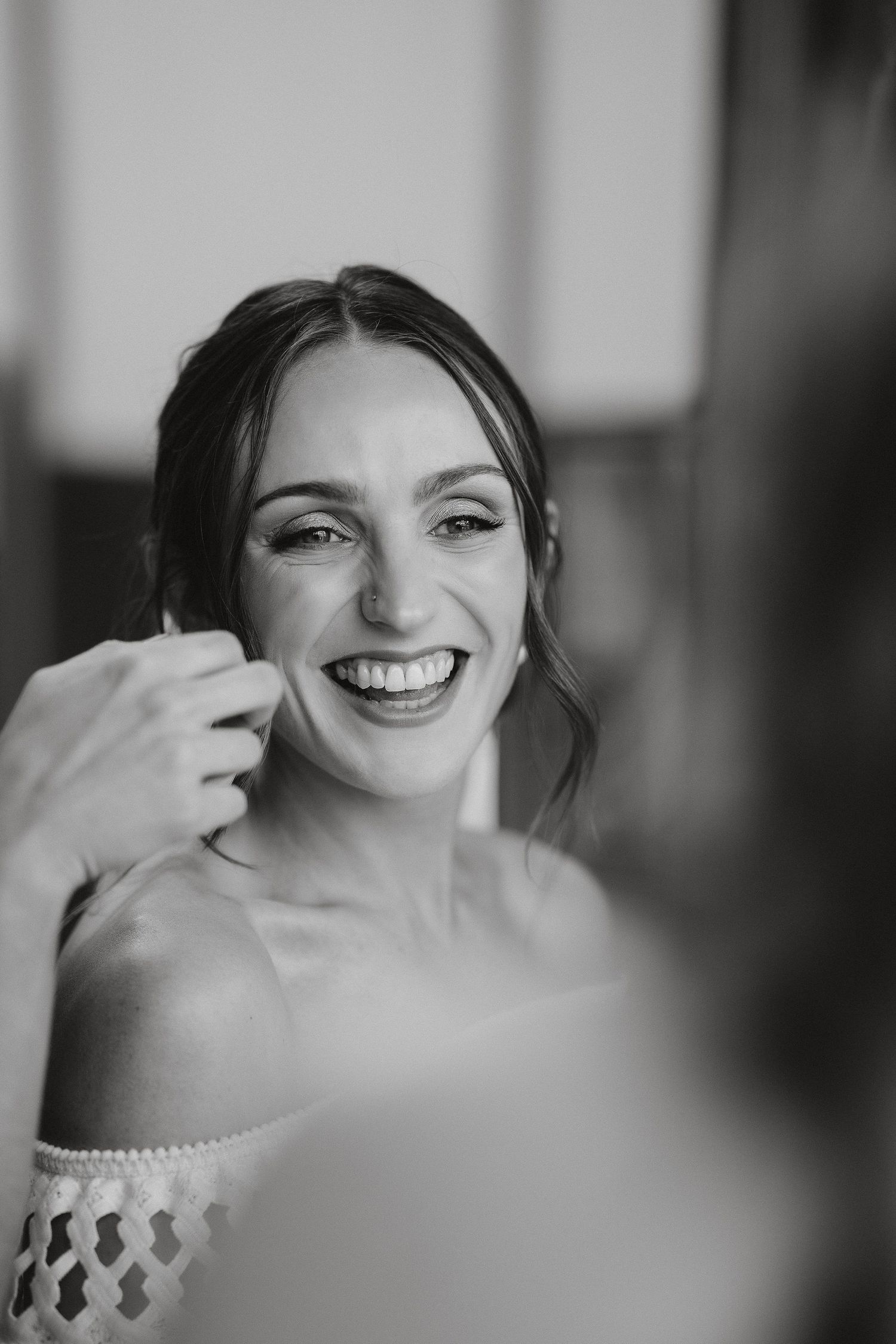 Black and white portrait of someone with a bright genuine smile during a wedding celebration.