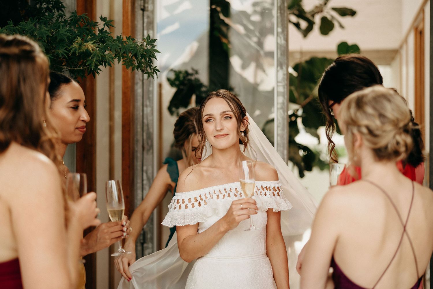 A group of friends in elegant attire gather outdoors holding champagne glasses during a special celebration.