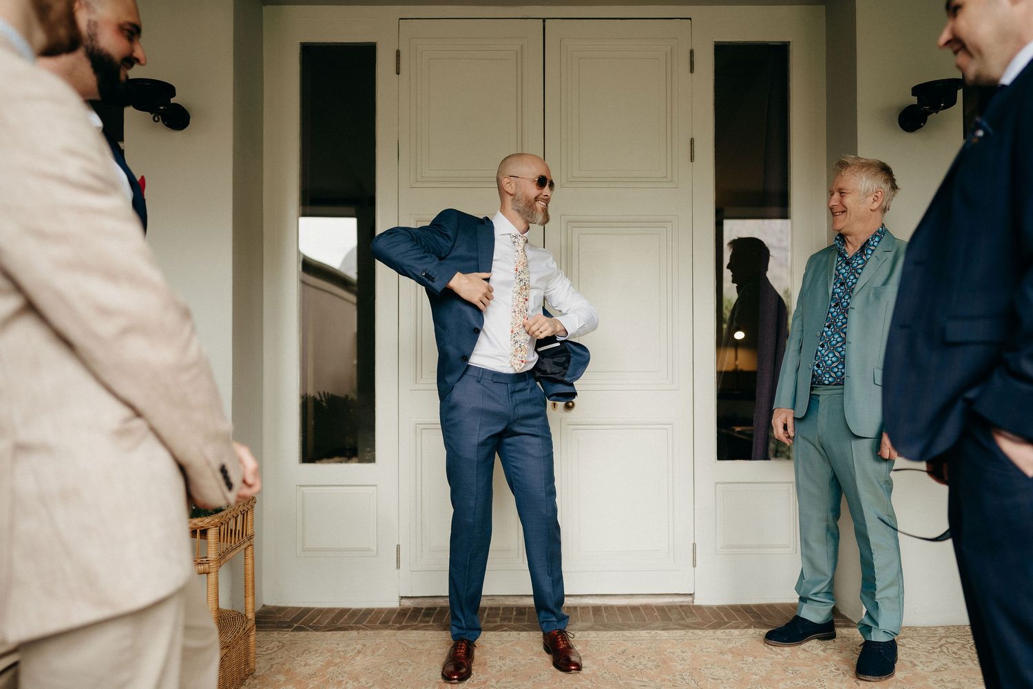 A joyful moment captured outside as people gather and interact on a white porch during a formal occasion.