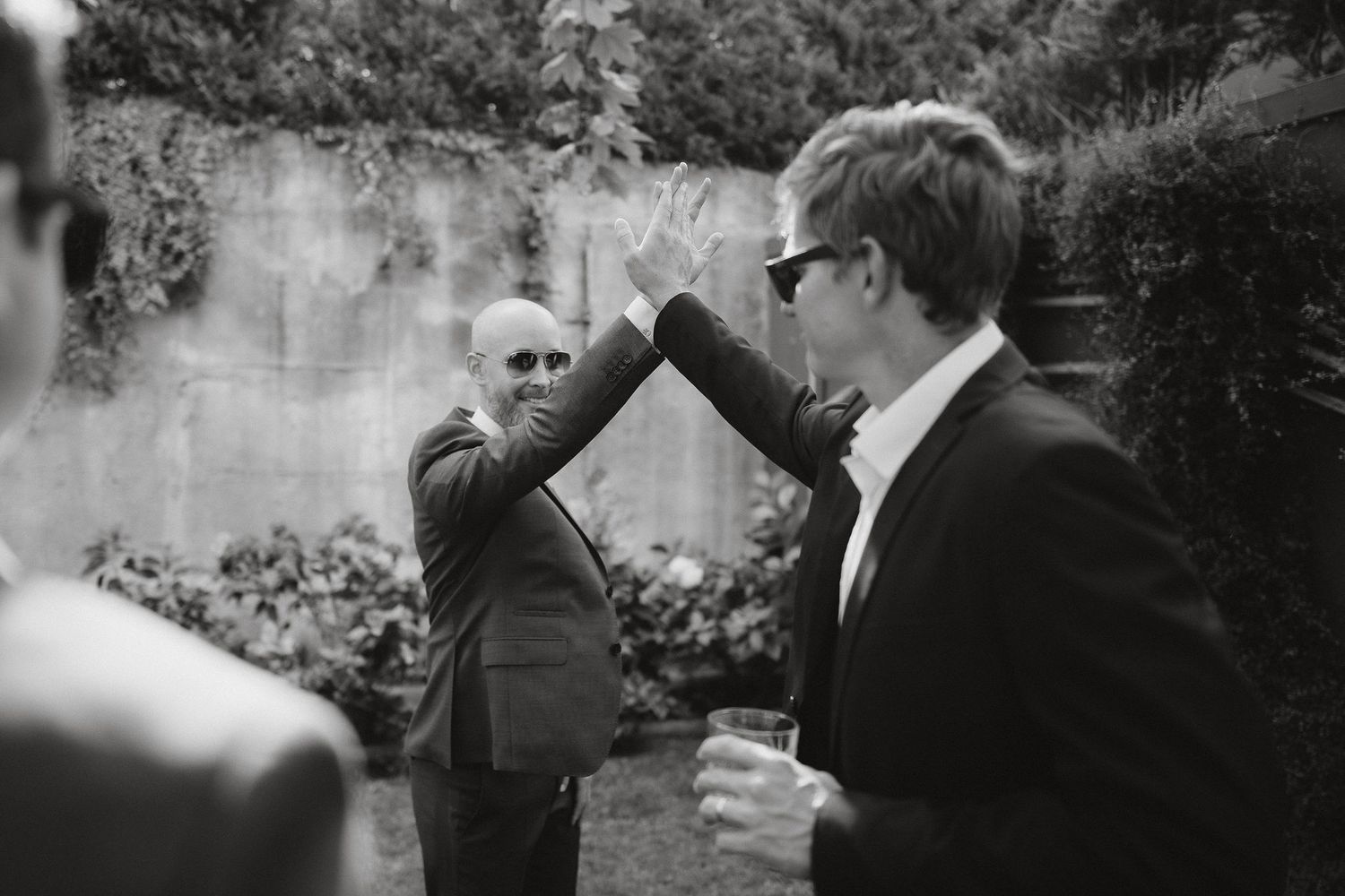 A vintage black and white photograph showing two men having an animated outdoor conversation in a garden setting.