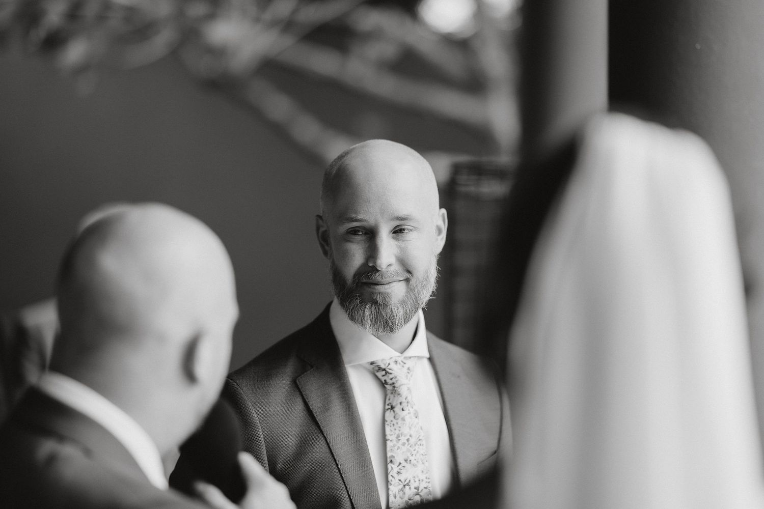 Black and white photo of two men in formal attire having a conversation at an indoor venue.