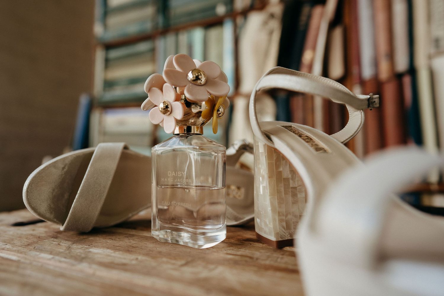 A small perfume bottle sits beside ceramic decorative items on a wooden surface in warm, natural lighting.