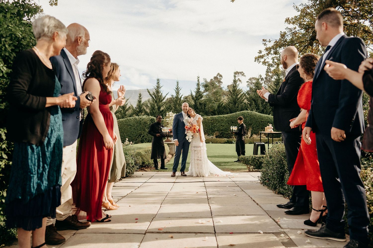Wedding ceremony taking place on an outdoor terrace with guests in formal attire watching from both sides.