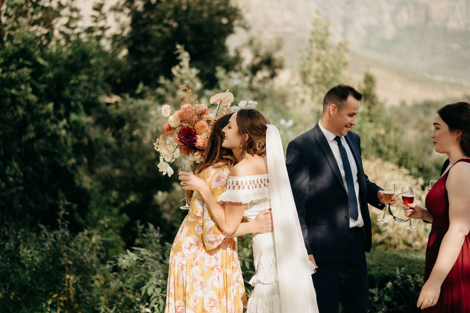 A candid outdoor wedding moment captured at sunset with guests mingling in a garden setting.
