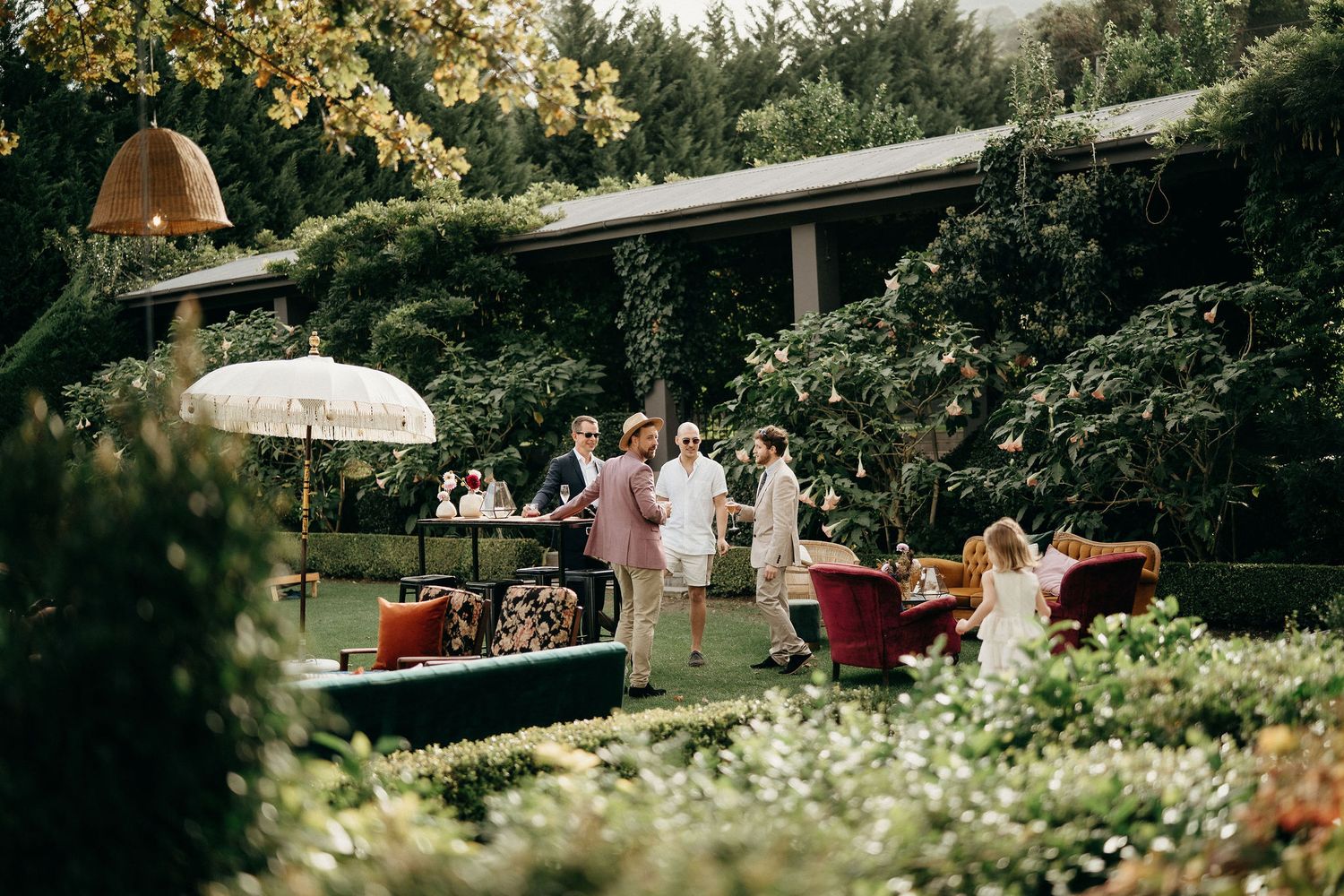 Elegant outdoor garden wedding reception with umbrellas and lush greenery on a sunny afternoon.