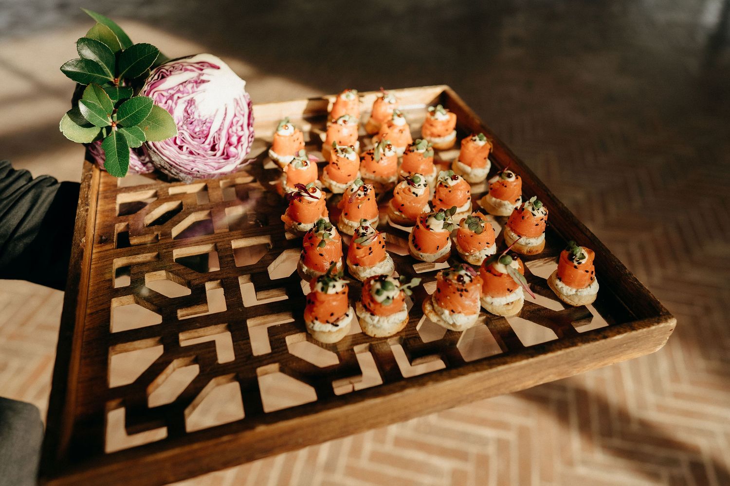 Elegant appetizer platter features rows of bite-sized hors d'oeuvres arranged on a decorative wooden serving board.