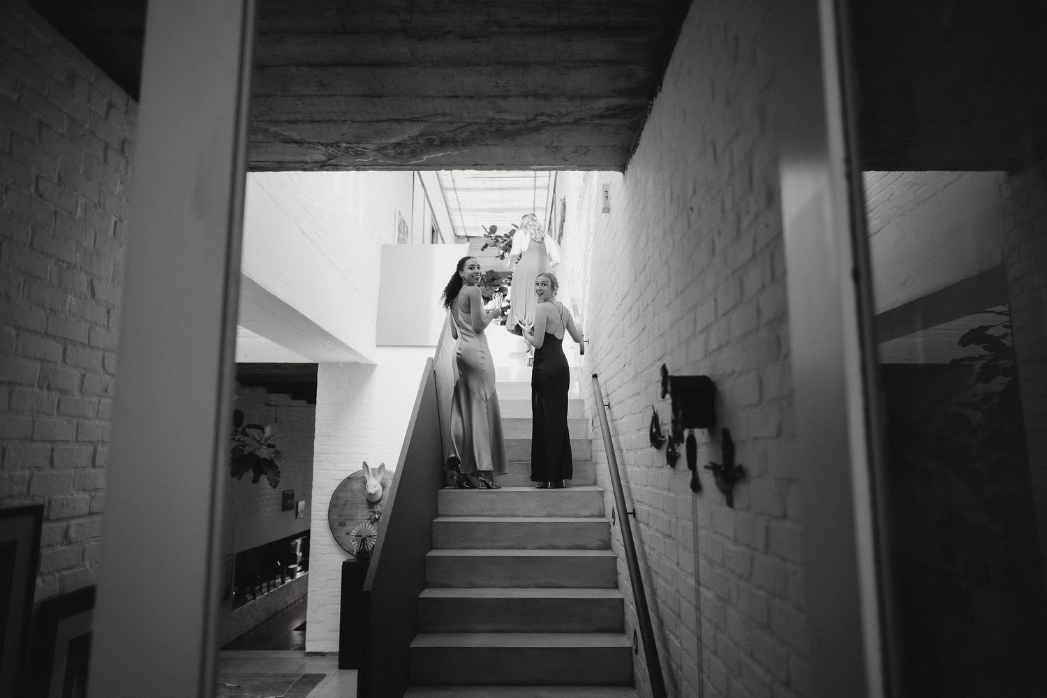 A dramatic black and white view up a stairwell with figures standing at the top creates an eerie atmosphere.