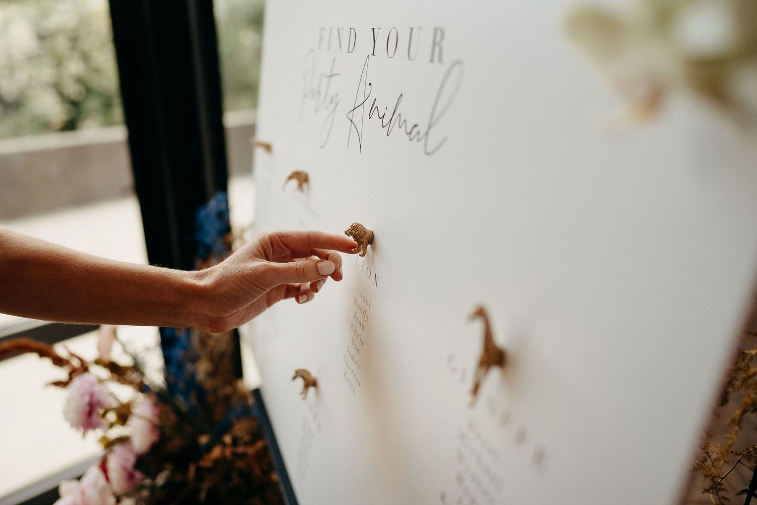A hand places delicate monarch butterfly decals on a white wall in soft sunlight.
