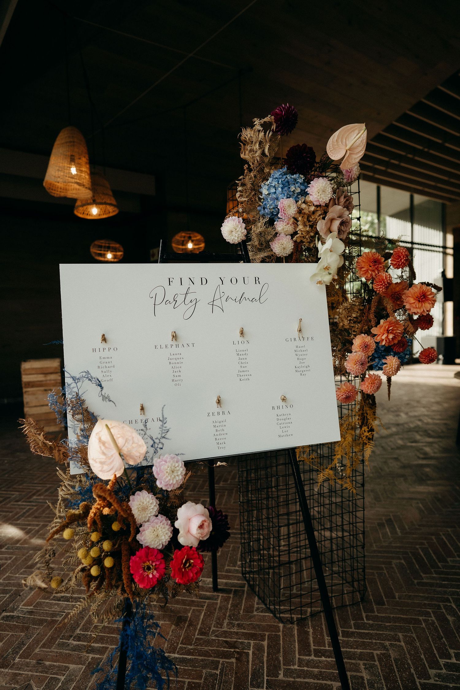 An elegant wedding seating chart display with dried flowers and warm lighting features ornate floral arrangements.