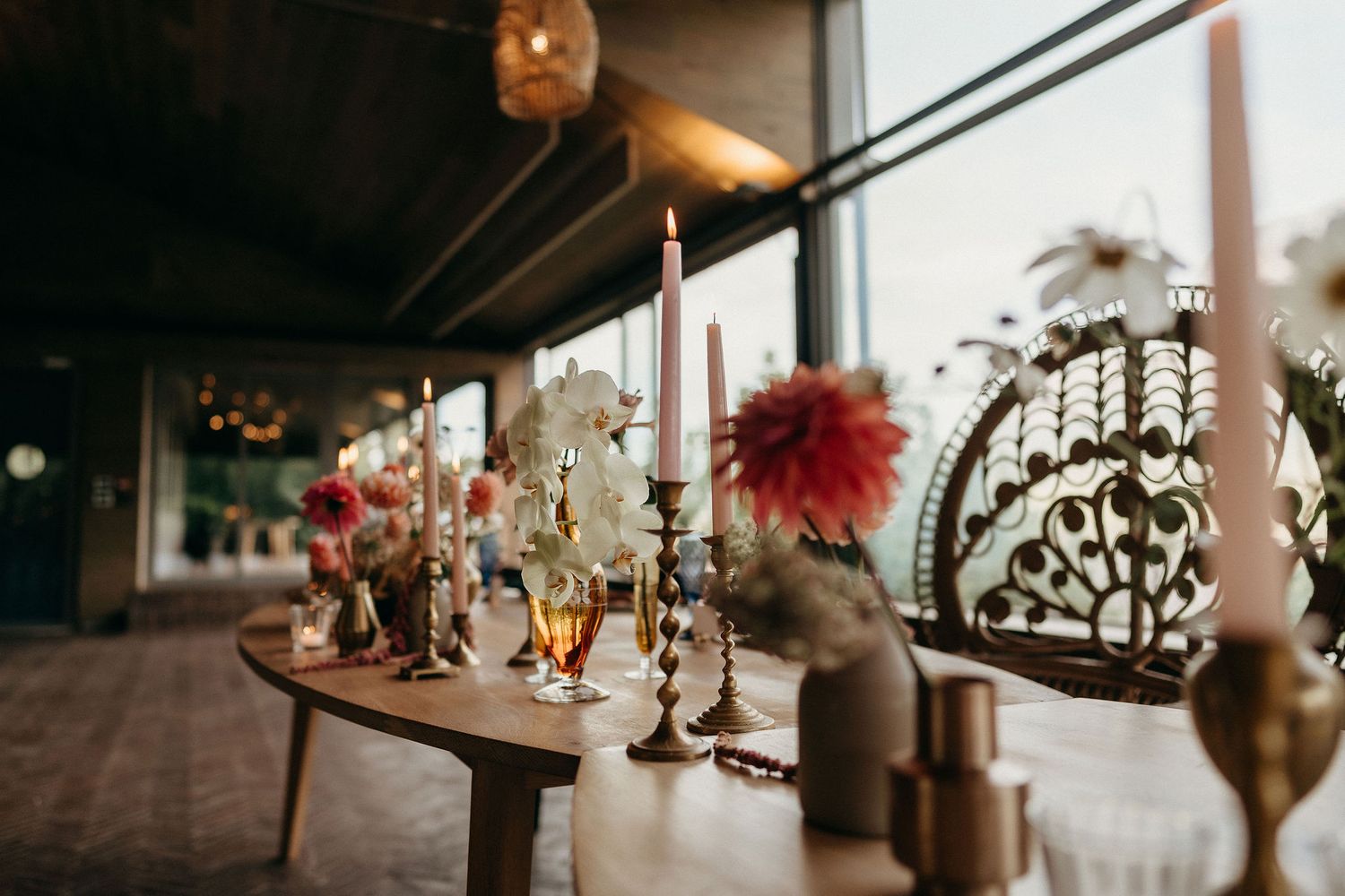 Vintage candlesticks and red feather decor arranged on wooden table in moody, romantic setting with ornate details.