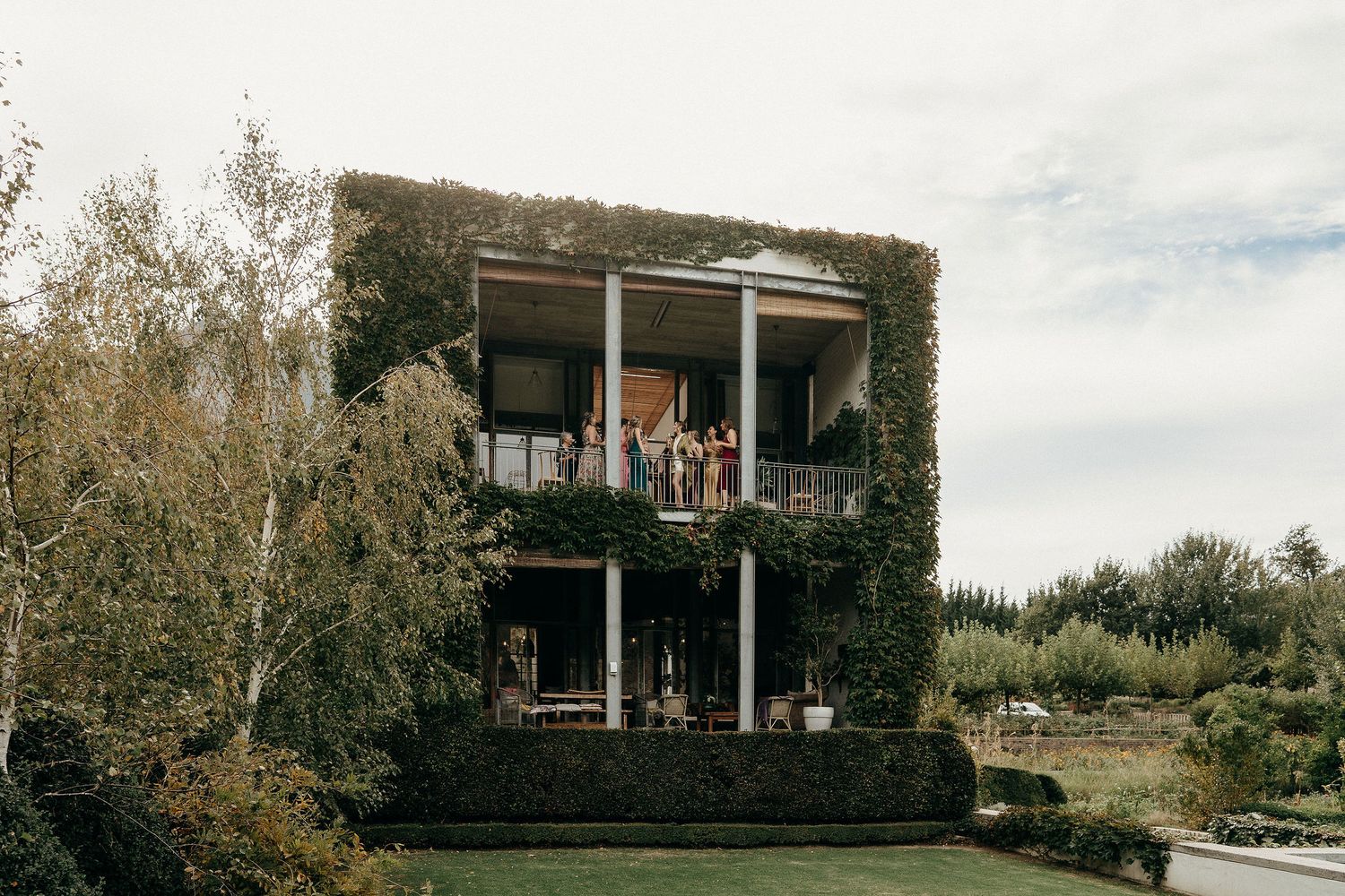 A two-story building covered in lush green ivy with people visible on both balconies.