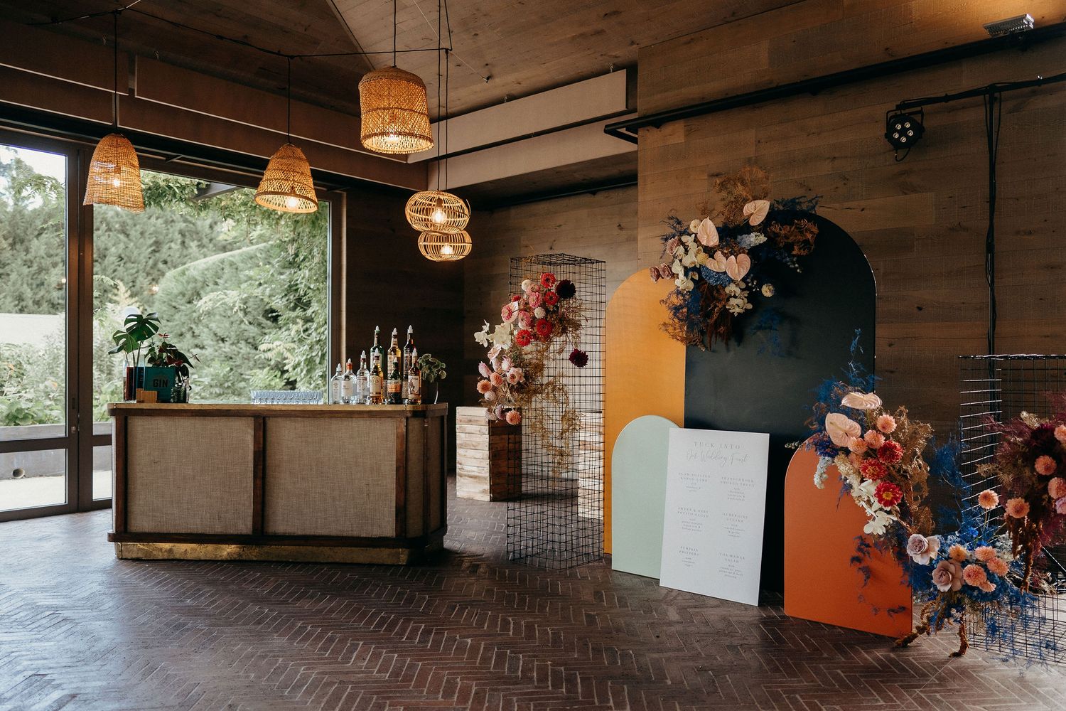 Modern wedding venue interior with wooden walls, geometric decor elements, and floral arrangements in rustic style.