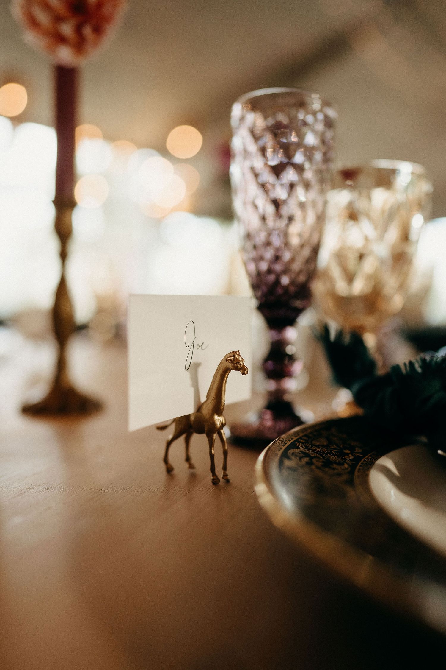 Elegant table setting with crystal glasses and small gold giraffe place card holder creating whimsical wedding decor.