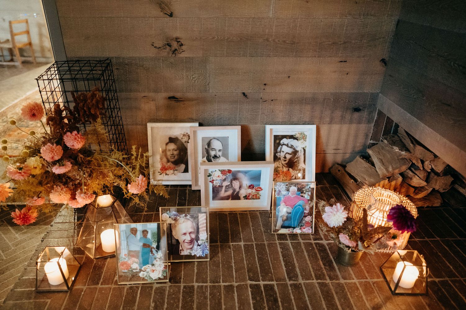 Vintage photographs arranged with glowing lanterns and pumpkins on wooden floor create a warm autumn memorial display.