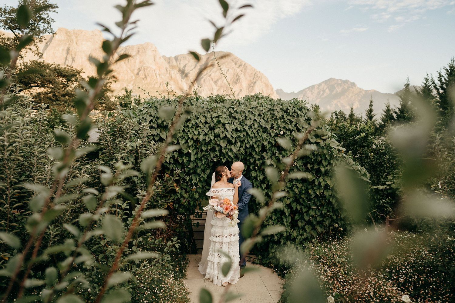 A romantic garden scene with mountain views and natural foliage framing the moment.