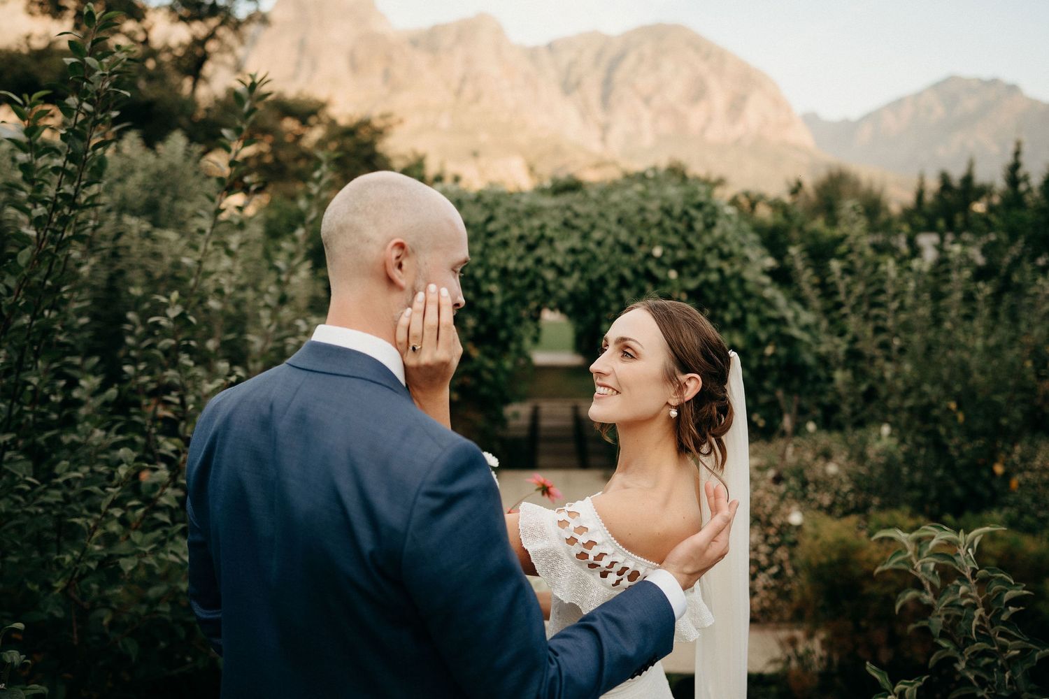 A couple shares an intimate moment during their wedding ceremony against a backdrop of majestic mountains and forest.