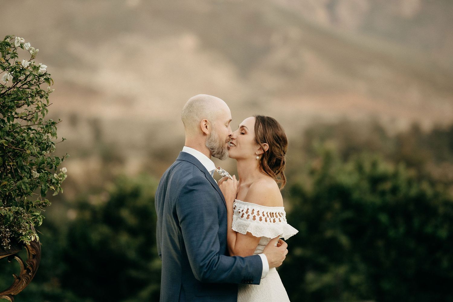 A romantic moment shared on a hillside with mountains creating a stunning backdrop.