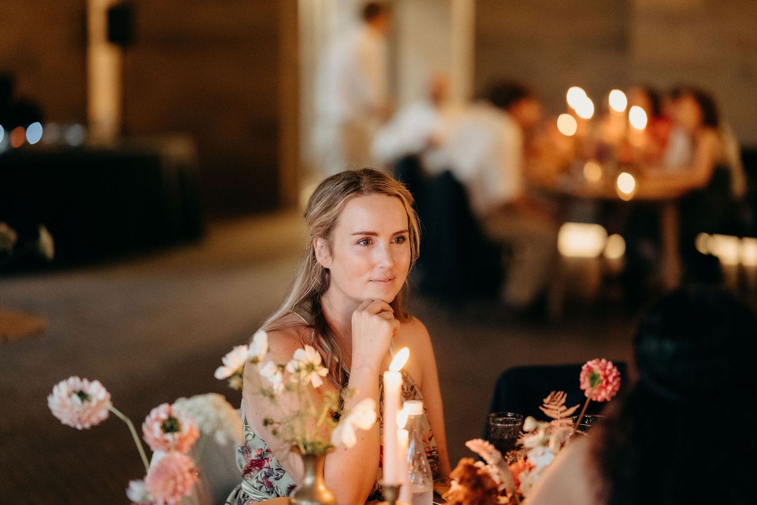 Candlelit table with floral arrangements and soft mood lighting at an elegant evening event.
