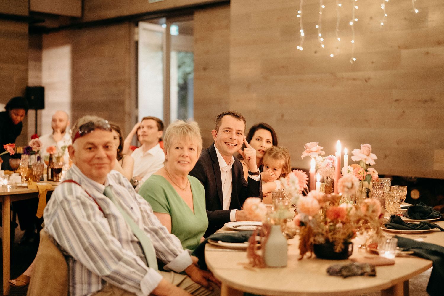 Dinner guests seated at an elegant table with warm lighting and floral centerpieces at an upscale restaurant.