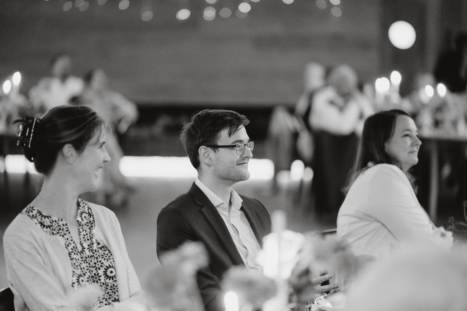 Black and white photo of guests seated at a formal event, with candlelit tables creating an elegant ambiance.