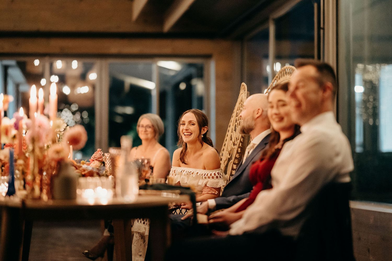 Guests seated at a dimly lit bar with glowing candles enjoy an evening gathering and celebration.