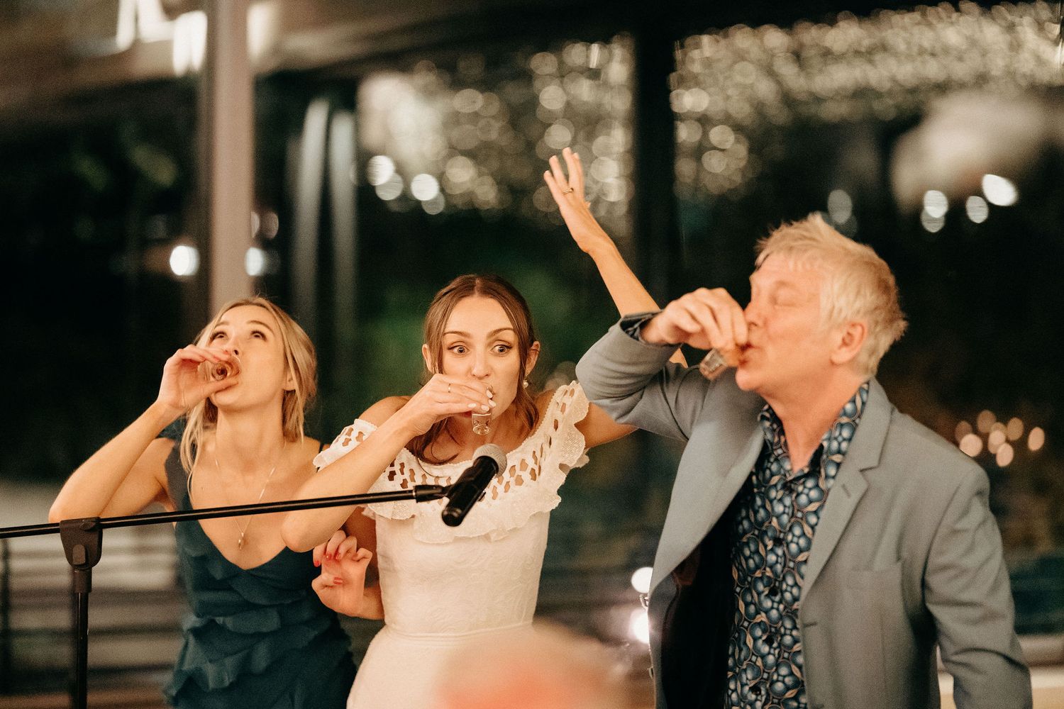 A joyful group celebrates together at a festive party under soft evening lighting.