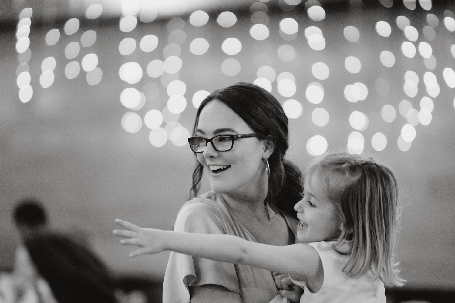 A joyful moment captured in black and white with twinkling bokeh lights in the background.