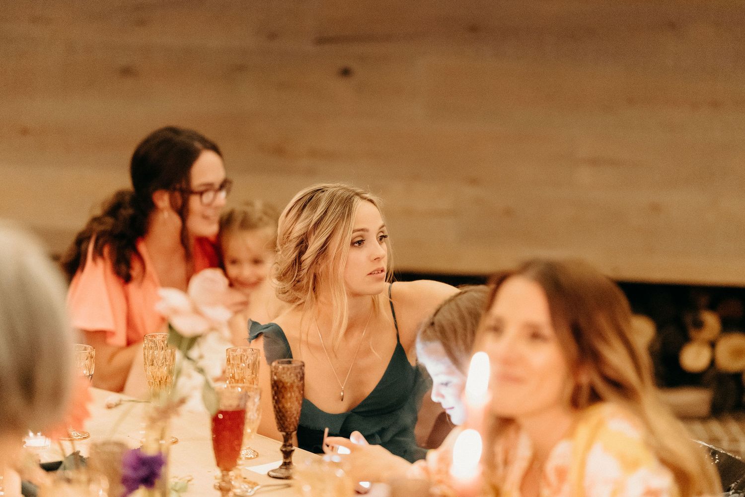 Friends enjoying a celebratory dinner gathering with drinks at a rustic wooden table.