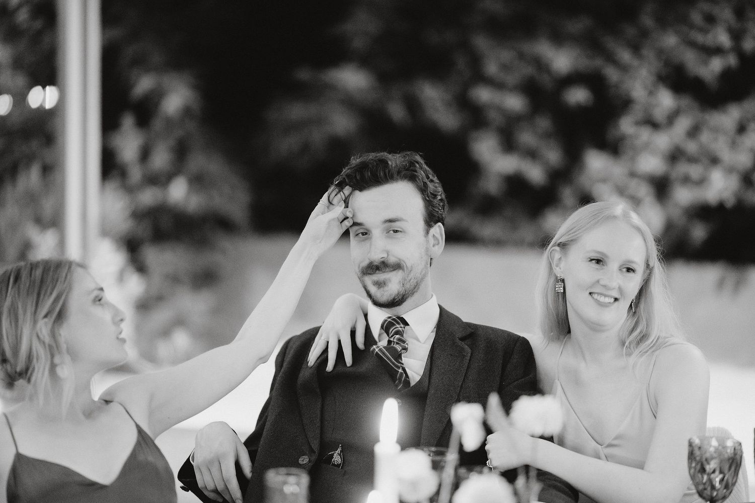 Black and white photo capturing joyful laughter during an elegant wedding reception dinner.