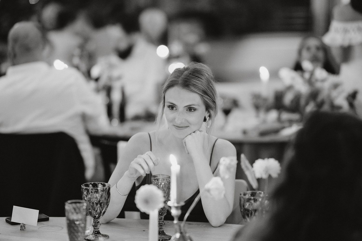 Guest sits alone at an elegant candlelit dinner table during a formal black and white reception event.