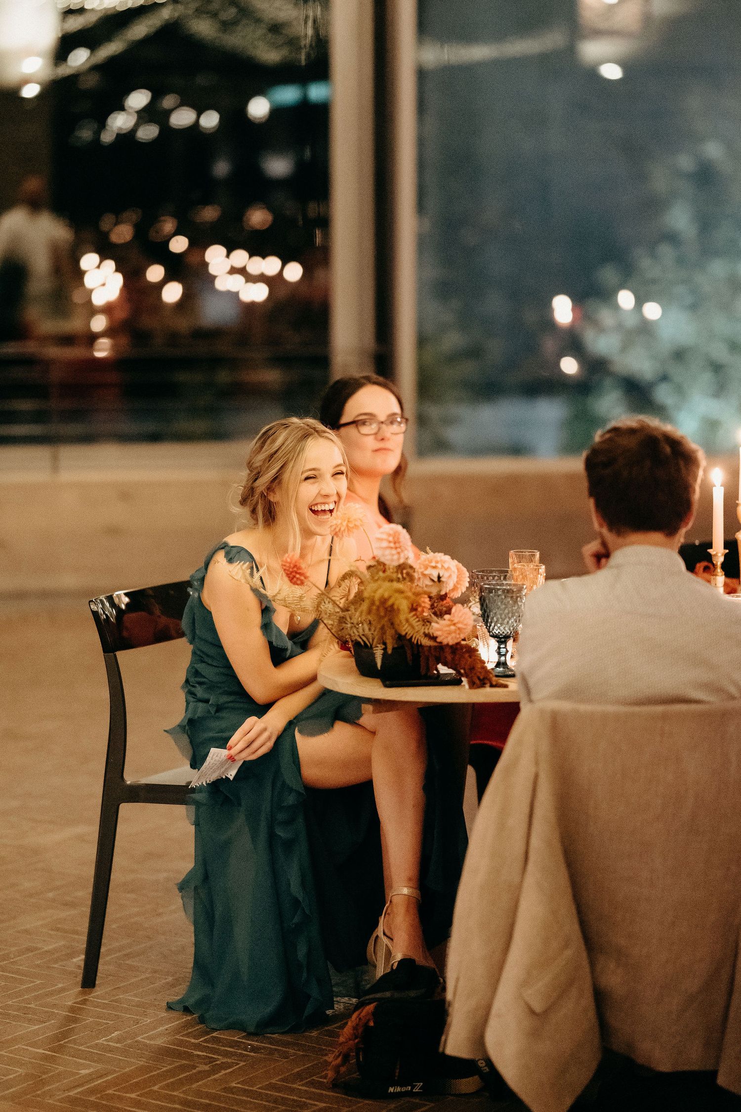 Friends enjoying an intimate candlelit dinner gathering at a restaurant with bokeh lights in background.