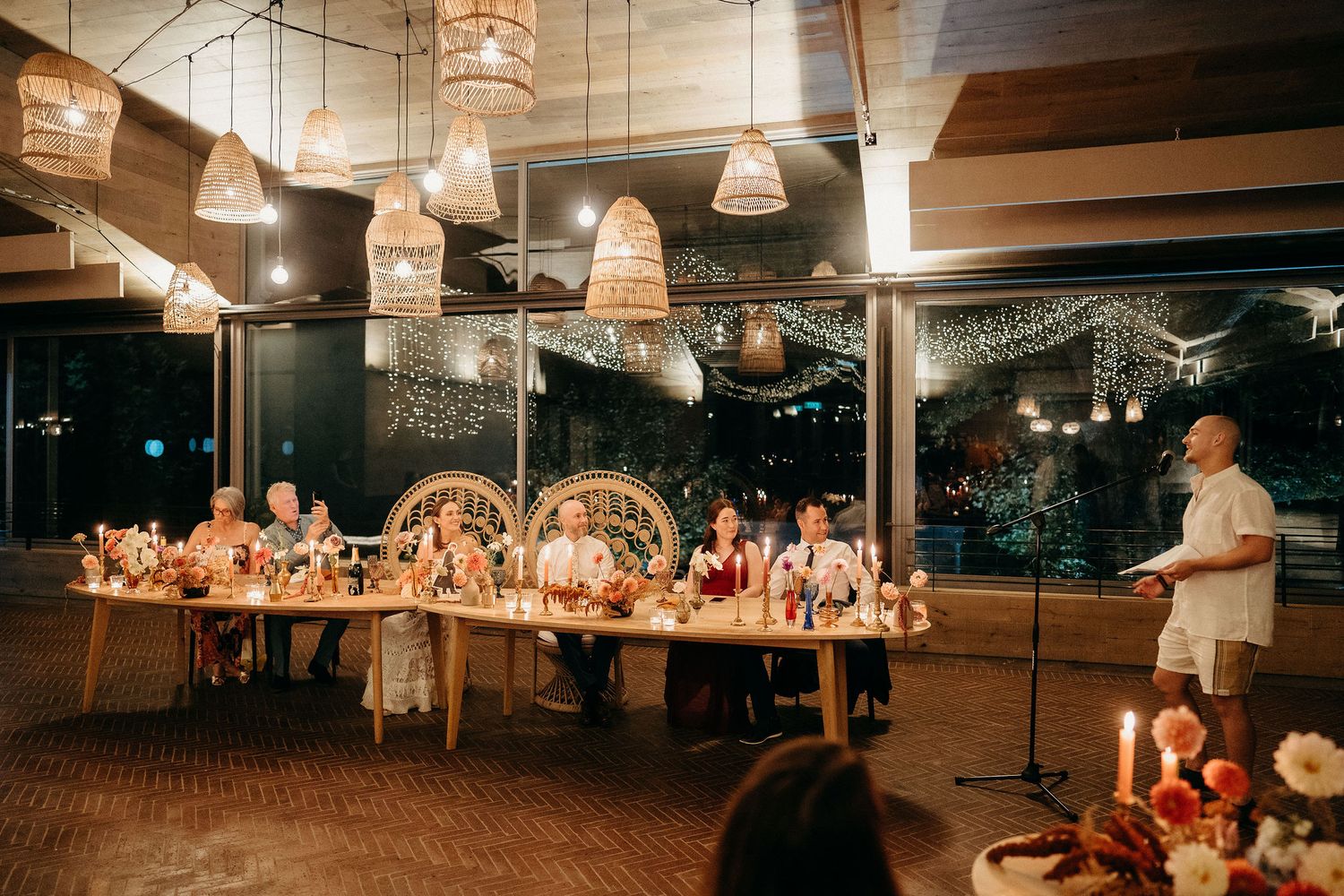 Warm-lit indoor reception venue with hanging basket lights illuminating a long dining table during evening celebration.