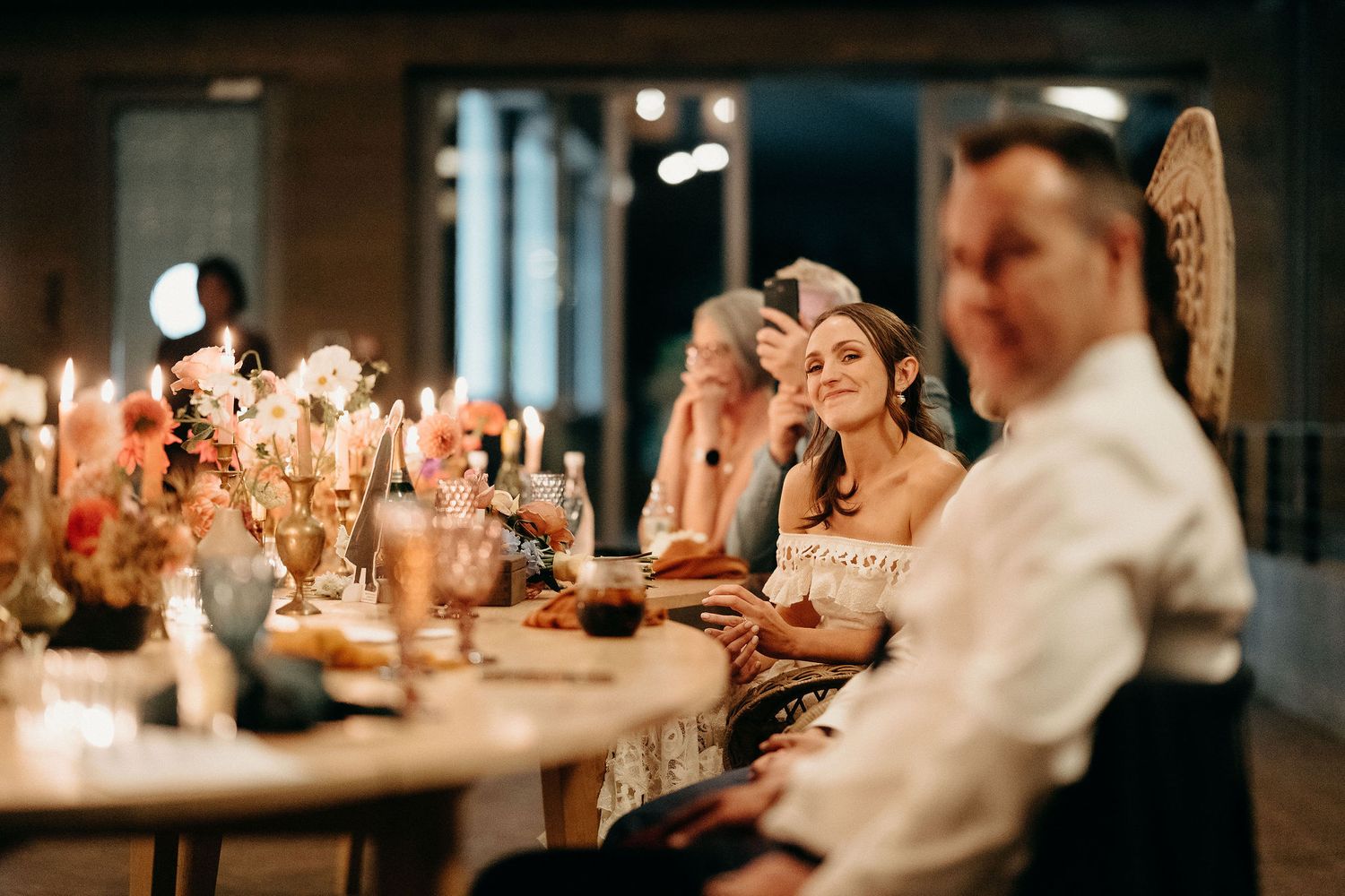 Candlelit reception dining scene with elegant table settings and warm ambient lighting creating a romantic atmosphere.