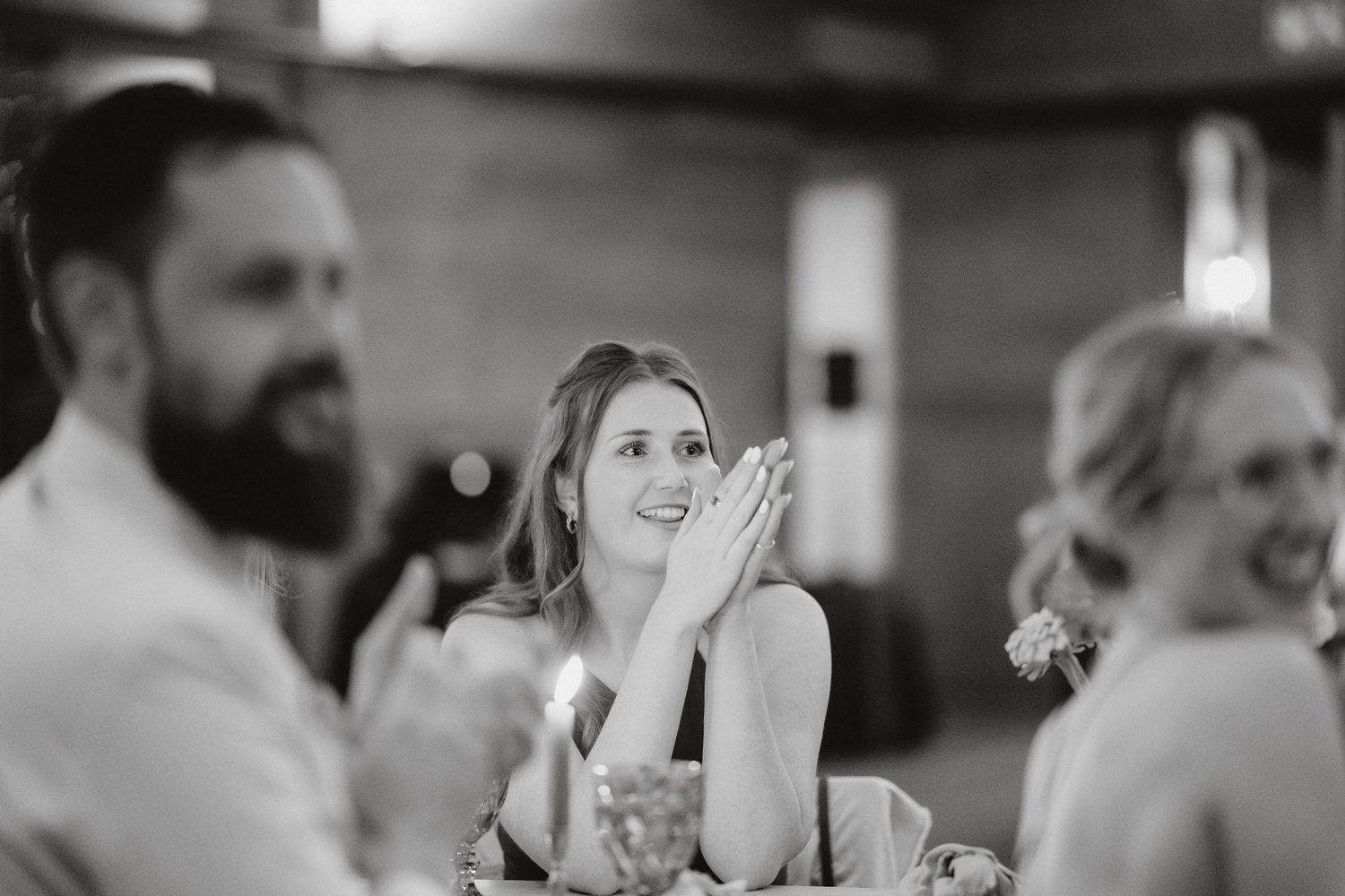 Wedding guests share a candid moment of joy and laughter during an indoor reception celebration.