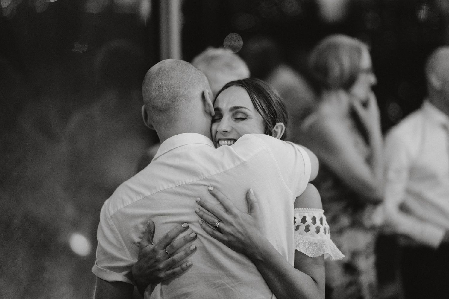 A joyful black and white candid photo of an emotional dance moment at a wedding celebration.