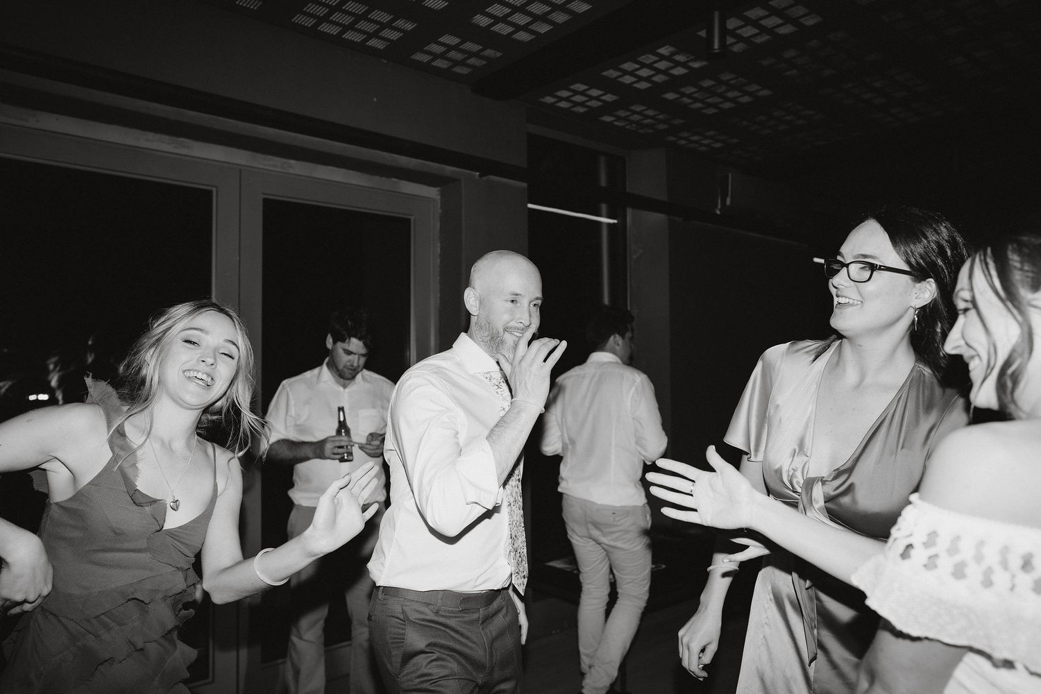 Black and white photo of people dancing and having fun at a party or celebration with joyful expressions.