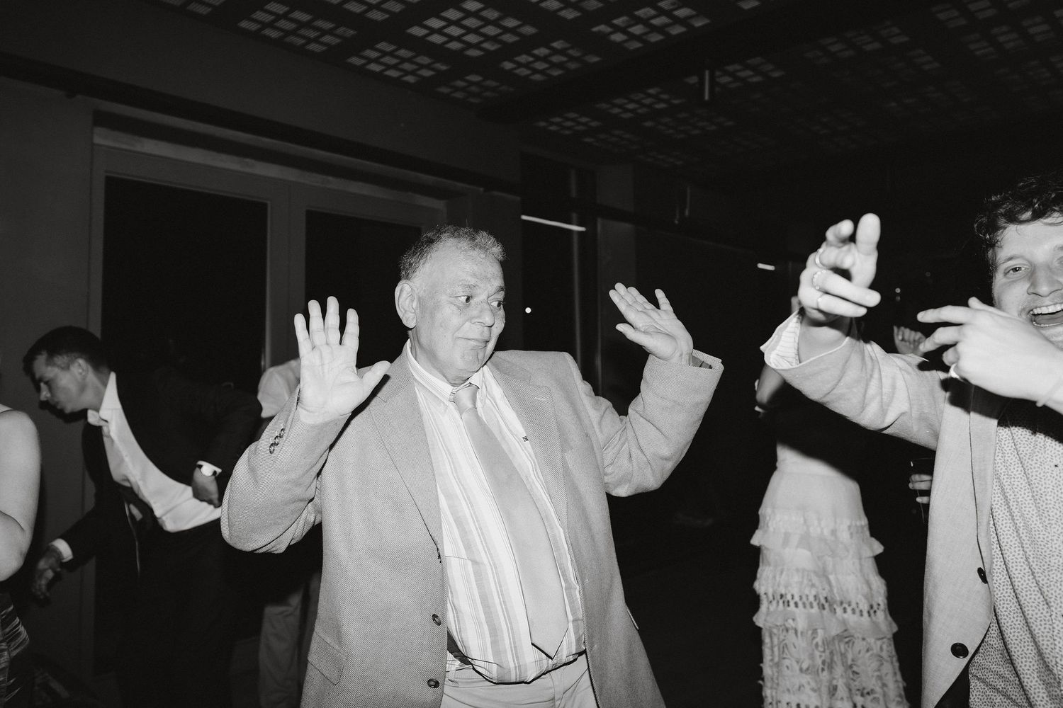 Vintage black and white photo of dancers with raised hands at a party or social gathering.