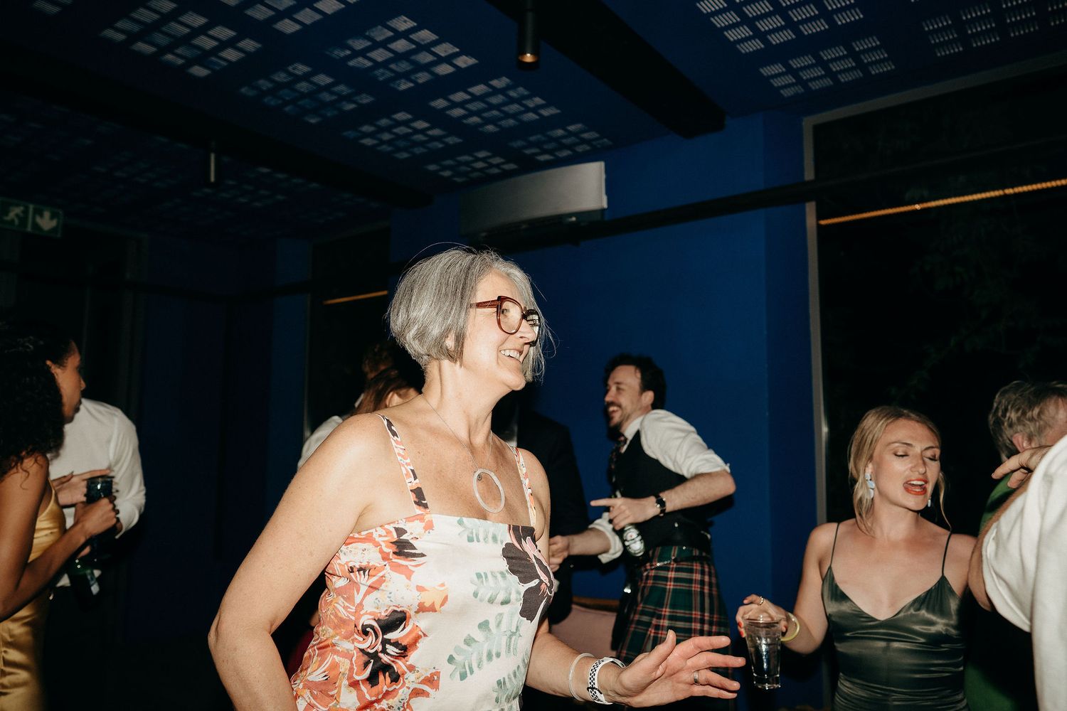 People dancing and having fun at a party celebration with blue walls and dark ceiling.