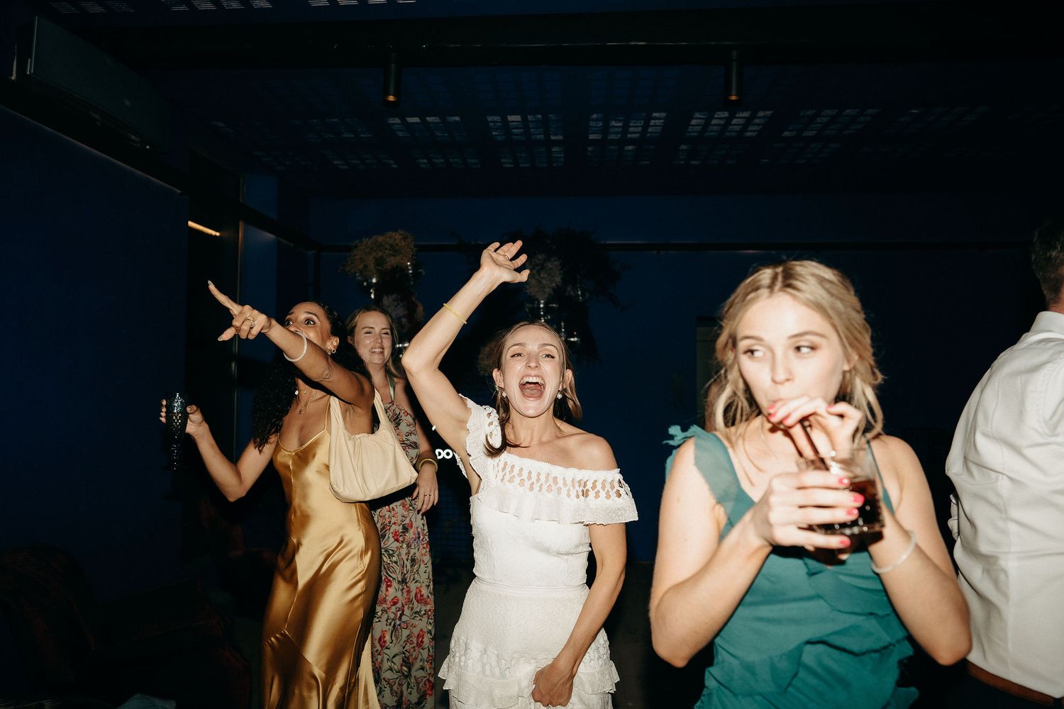 Energetic partygoers dancing and celebrating at a nighttime event with drinks in hand.