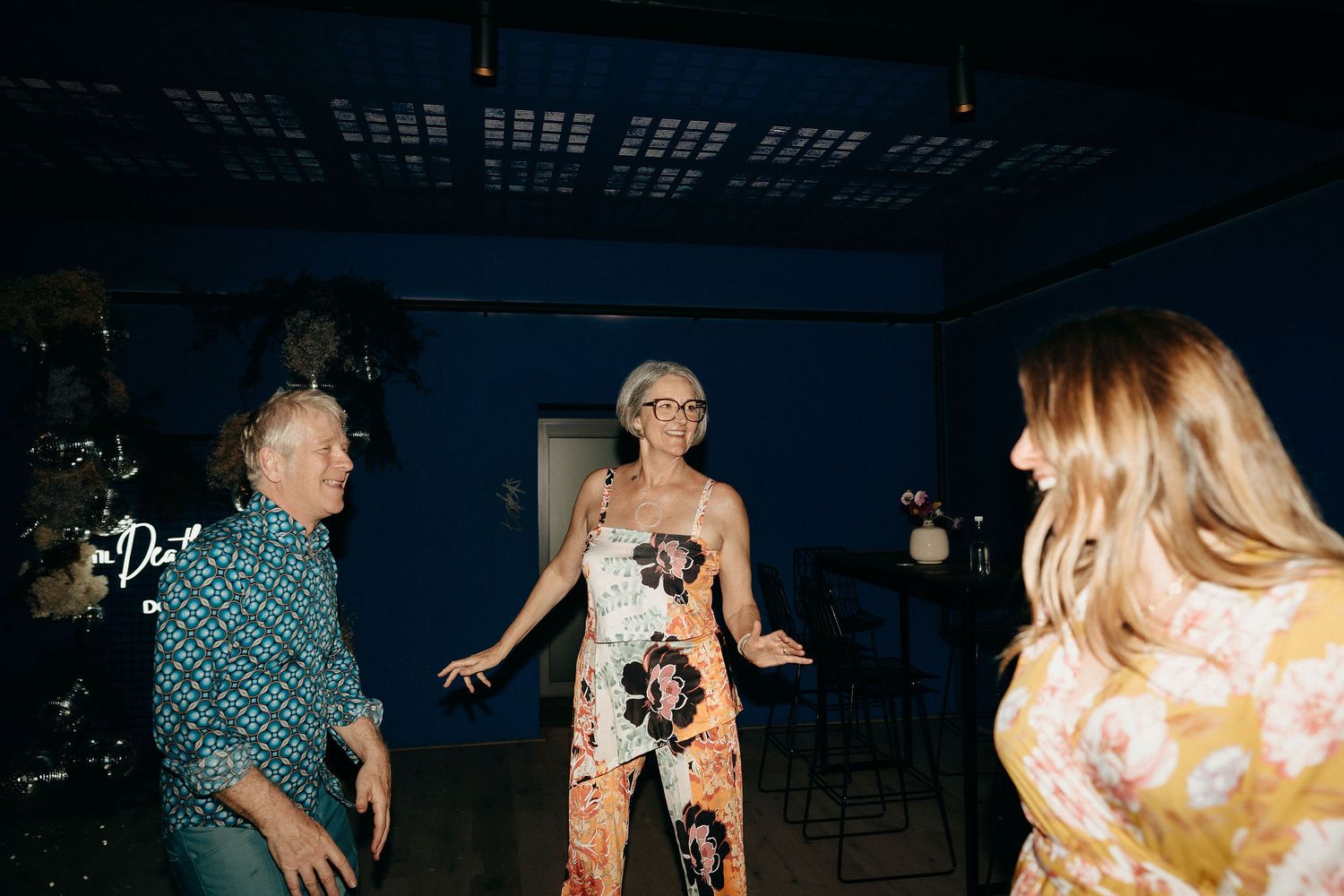 People dancing together at a nighttime party with colorful outfits and ambient lighting.