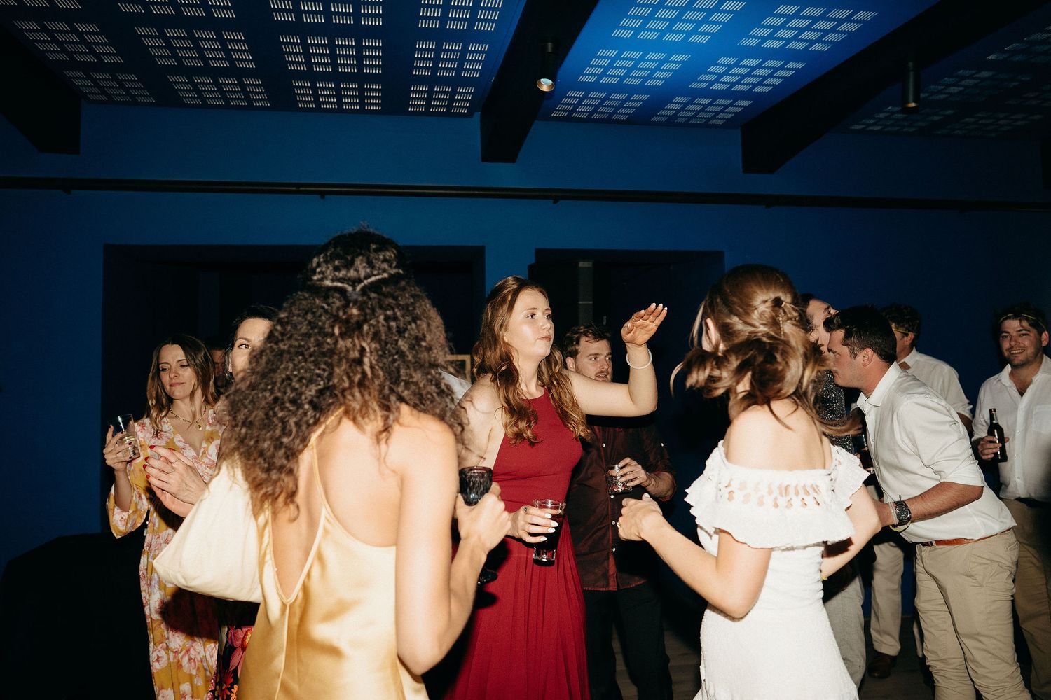 People dance and celebrate on a darkened dance floor at an indoor party event.