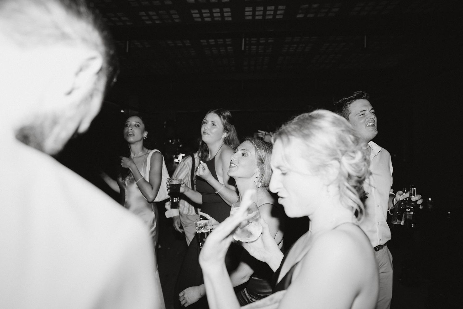 Black and white photo of guests dancing and laughing at a lively party celebration.