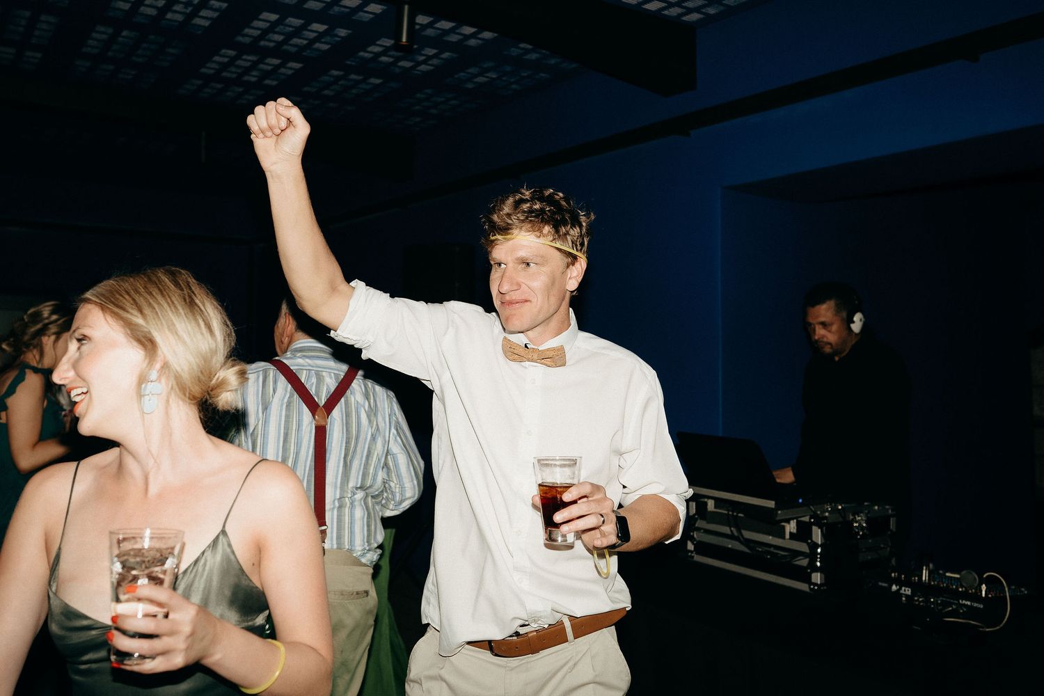 People dancing and enjoying drinks at a nightclub with a dark blue lighting atmosphere.