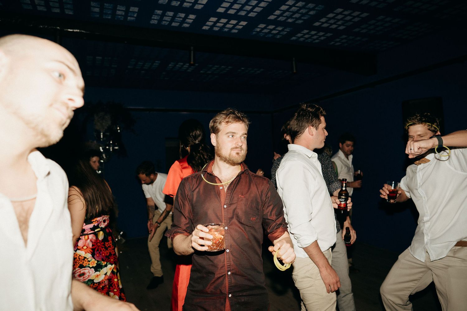People dancing and socializing at a dimly lit nightclub party with flash photography.