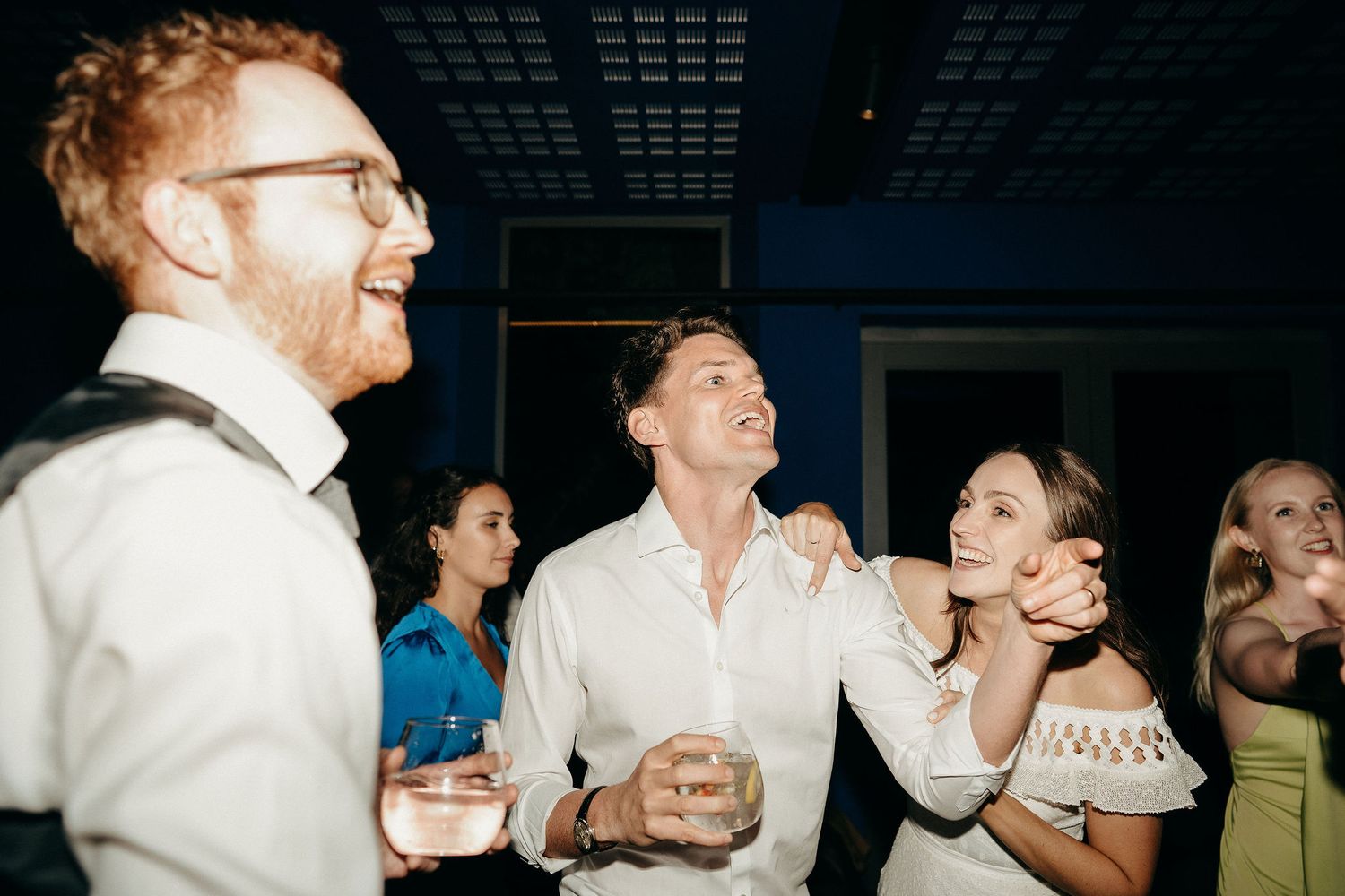 People enjoying themselves at a party with drinks and laughter, captured in candid nighttime celebration moment.