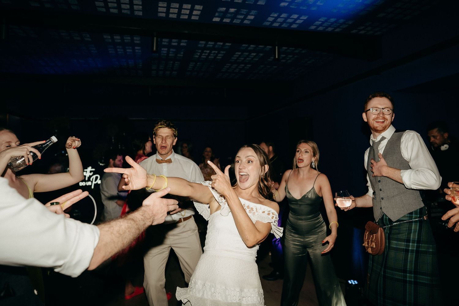 Wedding reception guests dancing and celebrating at a lively party with Scottish attire and festive atmosphere.